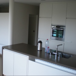 Nieuwe keuken met graniet en kleur snow white en achter glazen deur badkamer . 